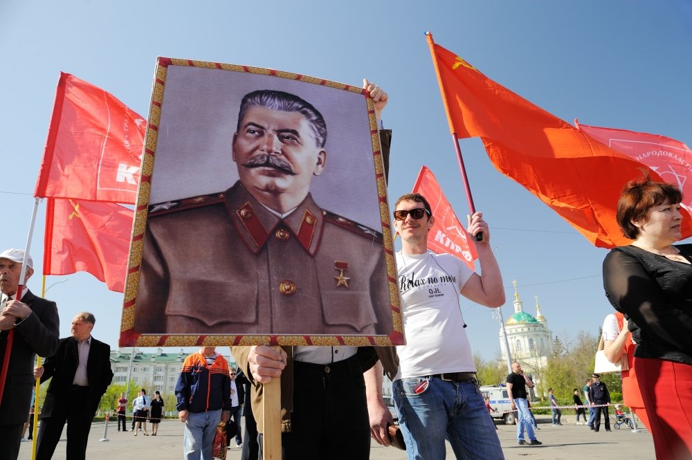Orel, Russia - May 1, 2017: May demonstration. Young men with Stalin portrait and red Communist flags. Source: Alexey Borodin/Shutterstock