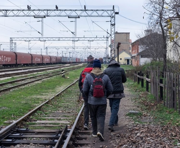 Migrants walking along train tracks in Serbia. Source: Shutterstock.