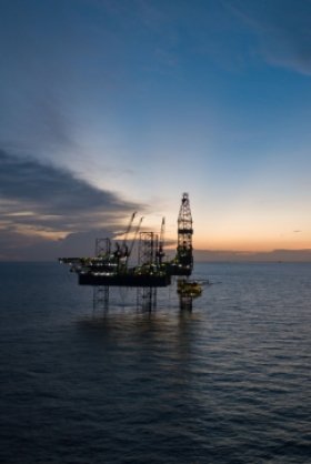 A picture of an offshore oil rig at sunset.