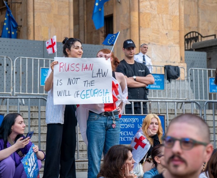 Protesters at Georgian parliament building in Tbilisi with flags and placards