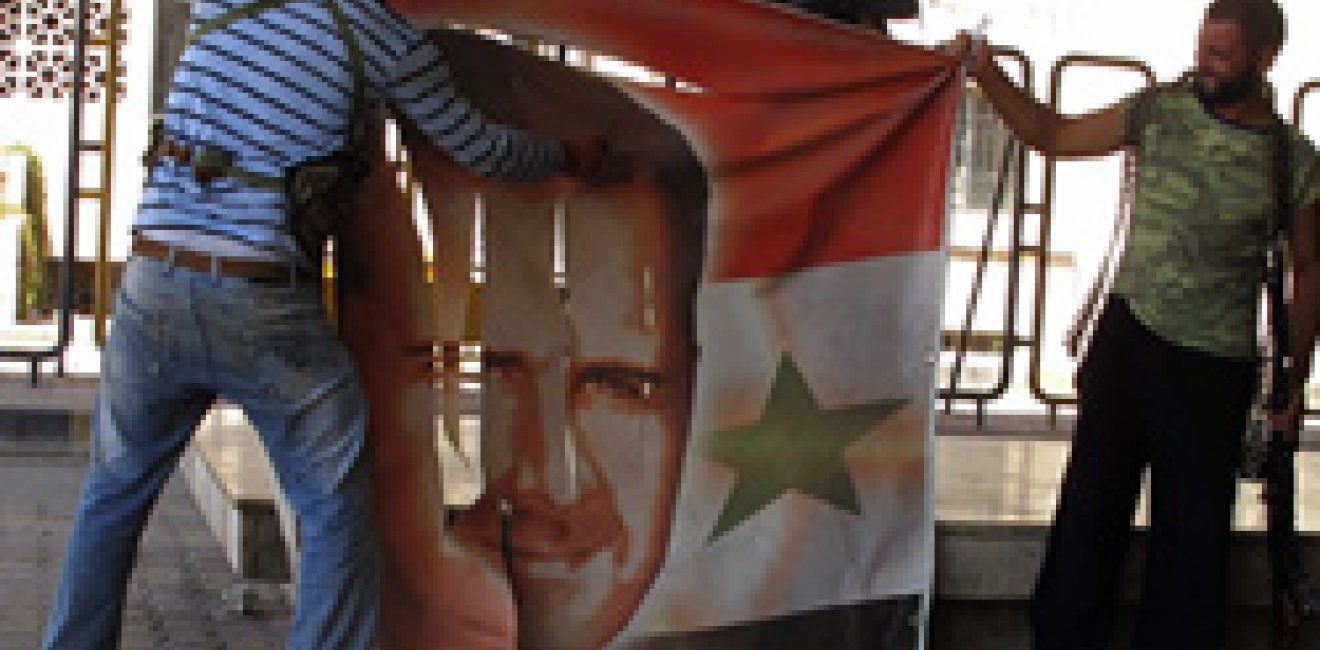 Free Syrian Army members tear a banner with picture of Syria's President Al Assad at Syrian border crossing building between Syria and Turkey at Jarablus