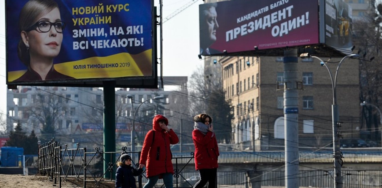 People walking near political billboards of Ukrainian candidates of presidential election, Kyiv.