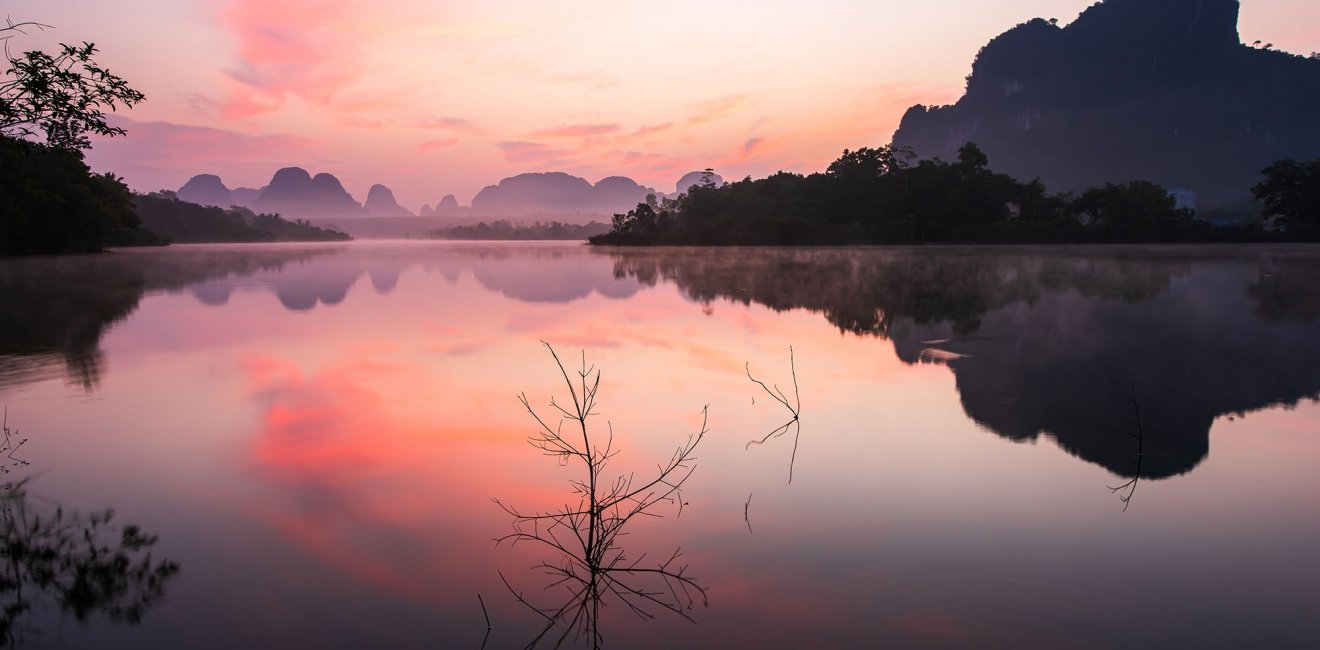 A sunset over a lake with mountains in the background.