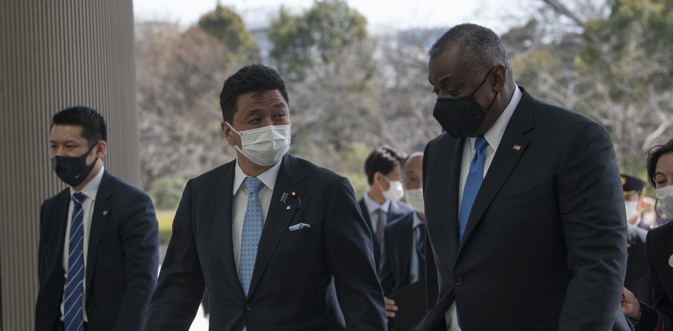 A group of men wearing medical masks talk as they they are walking into a building.
