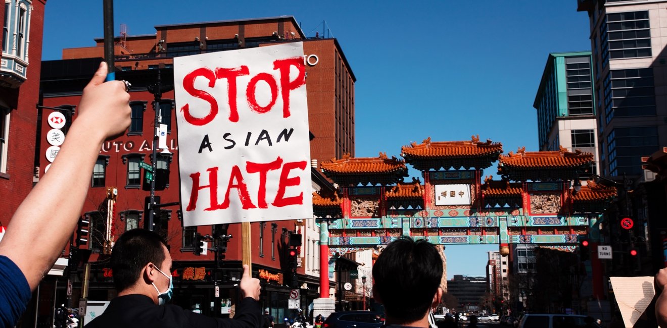 People march in the streets of Chinatown, one holding a sign that reads Stop Asian Hate