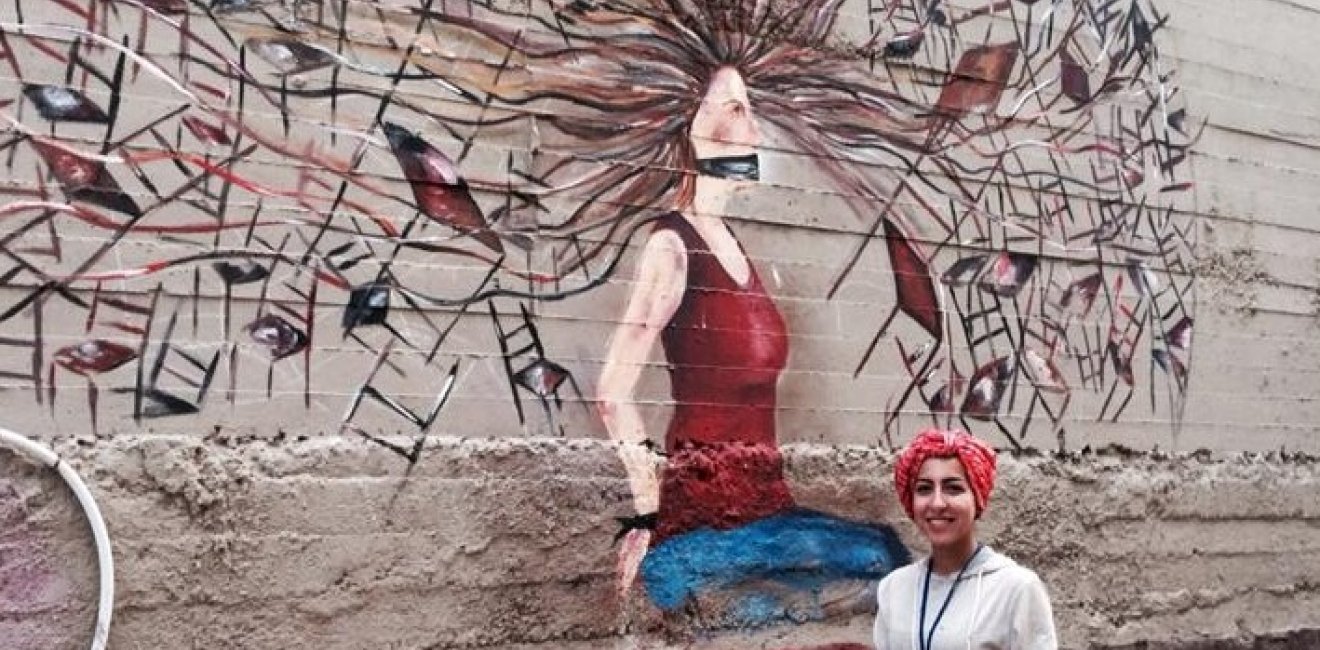 Street Artist Nour Qussini with her artistic piece at the WOW Baladak Street Art Festival in Amman, Jordan: Women on Walls: From Fear to Freedom, 2014. 