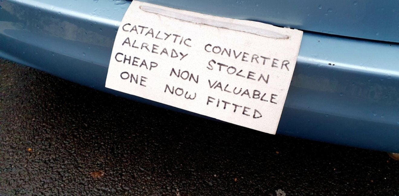 Sign on vehicle warning potential criminals that the catalytic converter has already been stolen and a cheaper part substituted