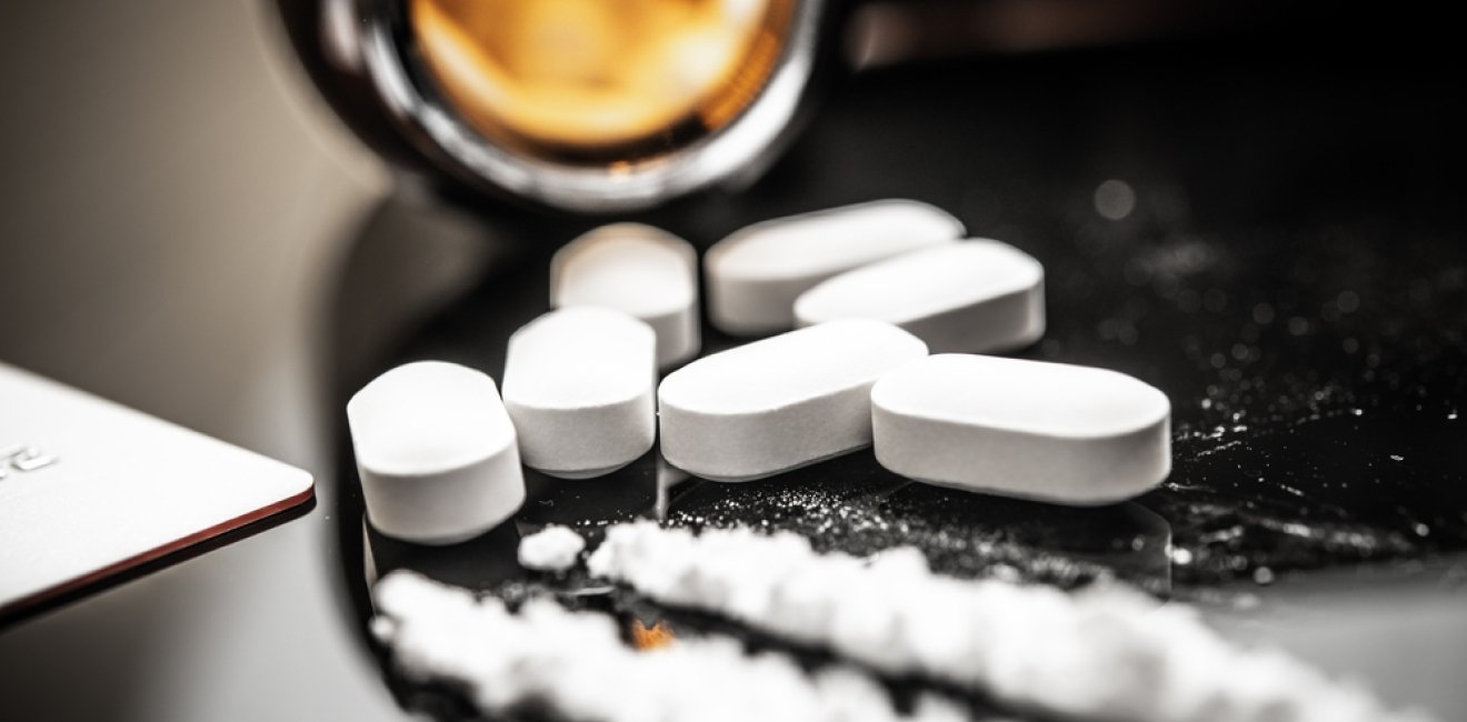 A detailed view of fentanyl pills and white powder on a reflective surface, illustrating the opioid crisis and prescription drug misuse. Subtle reflections and contemporary elements enhance the scene.