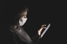 Woman with face mask staring at cell phone