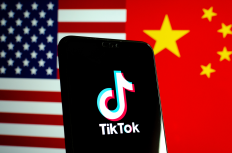 October 25 2019: TikTok app logo on a smartphone screen and flags of China and United States. Tiktok WeChat are banned. Apps are in centre of US - China tensions and security concerns.
