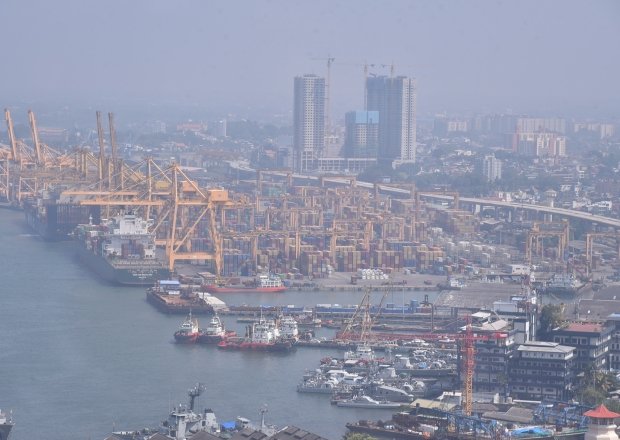 An aerial view of a port with cranes, ships, and skyscrapers.