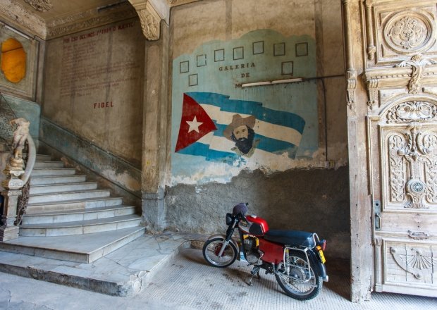 The image shows a painting of Fidel Castro on a worn-down wall in Old Havana