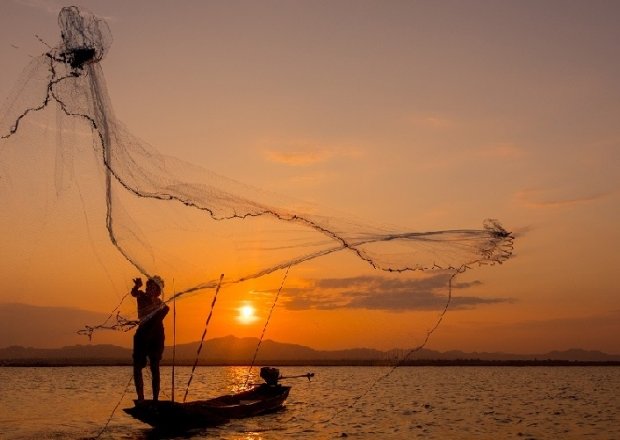 Silhouette Fisherman Throwing Net On Lake Stock Photo
