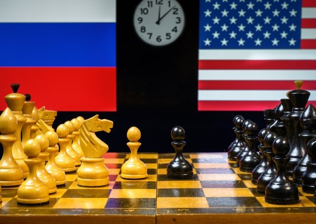 Chess board in foreground, US and Russian flags in background