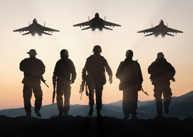 Soldiers walking away from camera with planes overhead