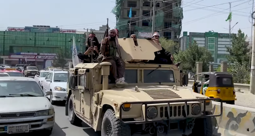Taliban fighters riding a tank in the streets of Kabul.