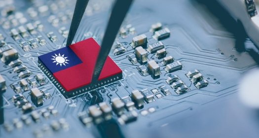 A circuit board with a pair of tweezers placing a part on the board, the part has the map of Taiwan on it.