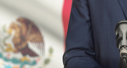 Man at Podium Before a Mexican Flag 