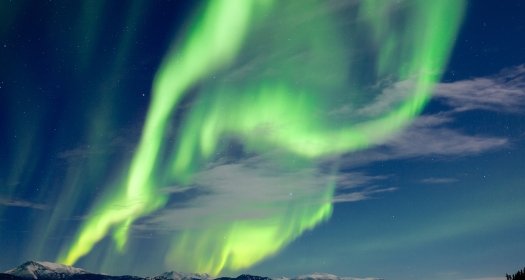 Spectacular Northern Lights or Aurora borealis or polar lights dancing over moon-lit winter landscape of frozen Lake Laberge, Yukon Territory, Canada