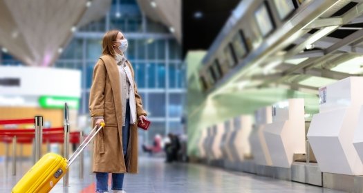 Woman with luggage stands at almost empty check-in counters at the airport terminal due to coronavirus pandemic/Covid-19 outbreak travel restrictions. Flight cancellation. Quarantine all over the world