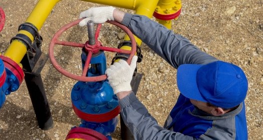 Image of a worker opening, closing the shut-off valves at the gas pumping station. Part of the photo is blurry.