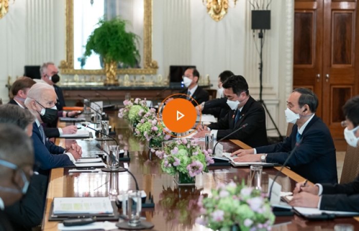 A group of men wearing masks sitting around a conference room table