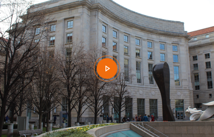 An image of the Woodrow Wilson Center with an orange play button