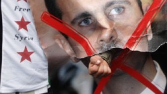 A demonstrator punches through a portrait of Syria's President Bashar al-Assad during a protest outside the Syrian Embassy in London