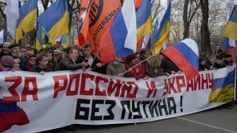 Boris Nemtsov stands at a protest holding a banner reading "For Russia and Ukraine Without Putin" in 2014.