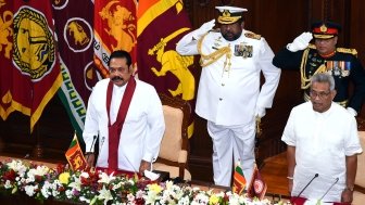 Prime Minister Mahinda Rajapaksa and President Gotabaya Rajapaksa stand in front of two soldiers at a swearing in ceremony