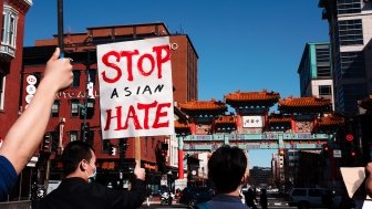 People march in the streets of Chinatown, one holding a sign that reads Stop Asian Hate