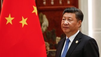 Xi Jinping standing next to the flag of China.