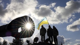 Ukrainian personnel standing on a tank with a flag