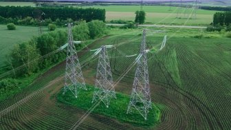 High voltage electric power tower in a green agricultural landscape at beautiful sunset