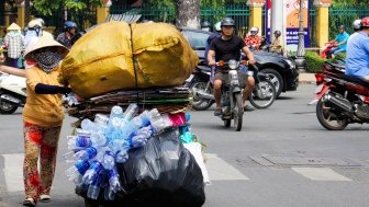 Overloaded motorbike with collected plastic bottles in traffic of Saigon