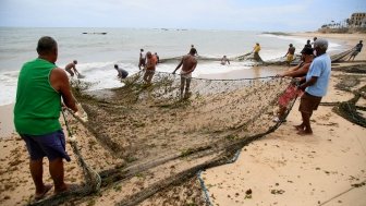 fishermen are seen during fishing with a trawl along the fishing colony on Pituba beach, in the city of Salvador.