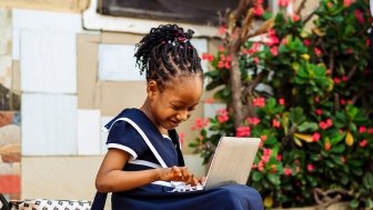 Young African girl working on a laptop computer. 