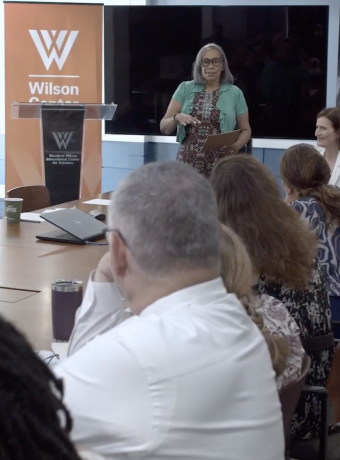 Presenter speaking to people seated at table