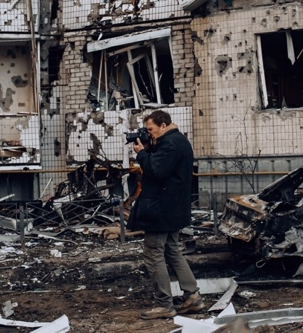 photographer in front of a bombed building in Kyiv, Ukraine
