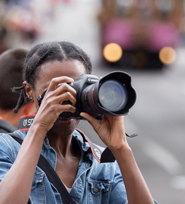 Portland, OR / USA - June 11 2016: Grand floral parade, African American female photographer taking pictures with canon dslr camera.