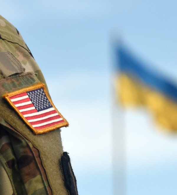 American soldier stands in front of the Ukrainian flag