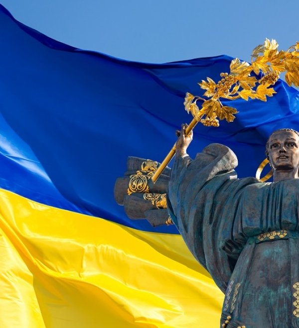 Monument of Independence of Ukraine in front of the Ukrainian flag. The monument is located in the center of Kyiv on Independence Square.