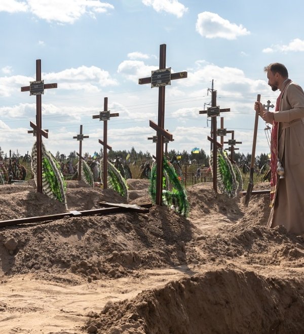 A priest overseas the burial of the remains of 13 unidentified and two identified people who were killed in the Bucha district during the Russian occupation