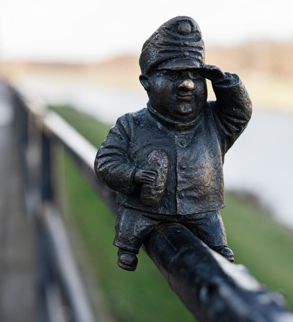 Small metal statue sitting on a fence 