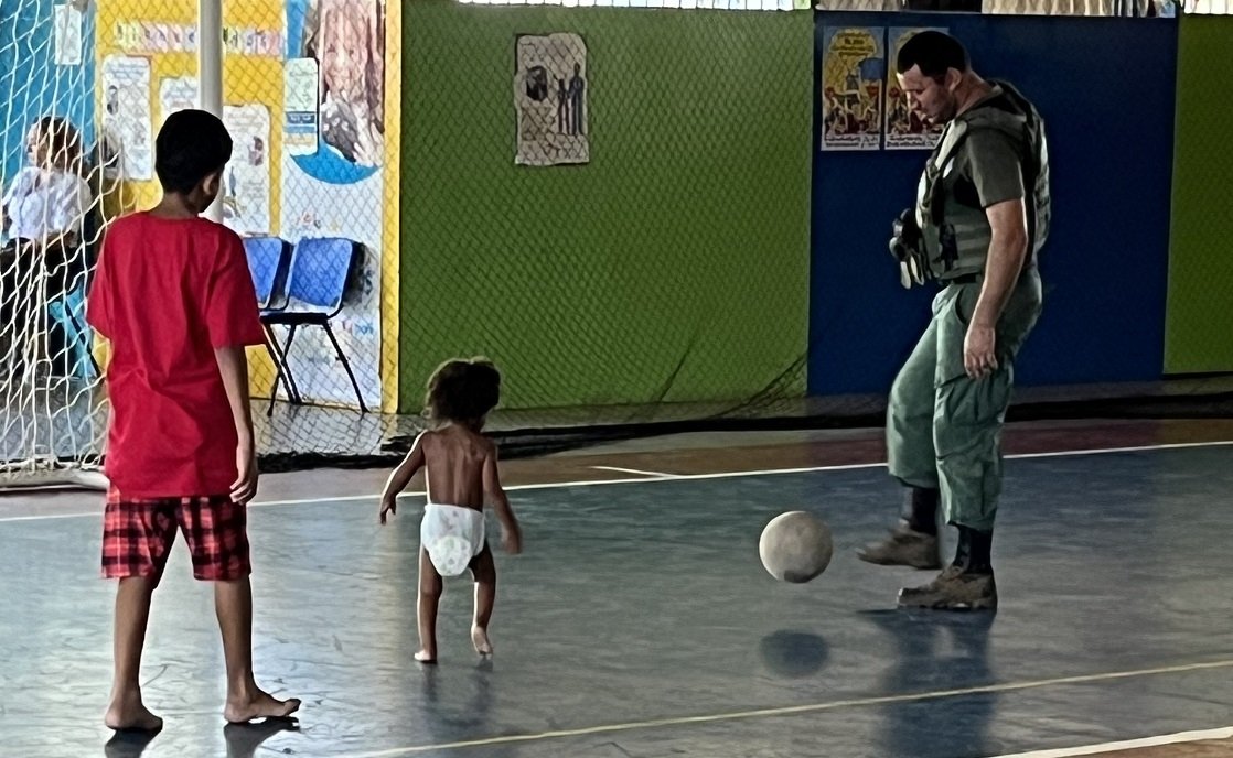 Kid and soldier playing soccer