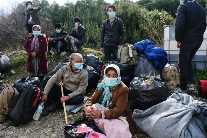 Refugees with masks awaiting transport in Greece