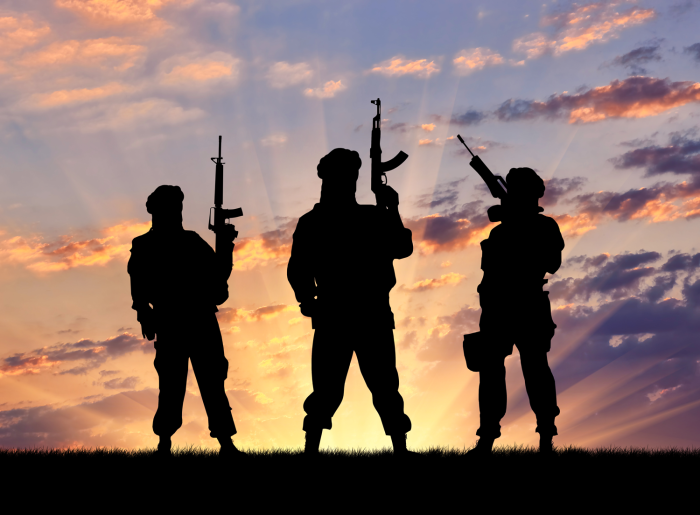 Concept of a terrorist. Silhouette terrorists with rifle at sunset