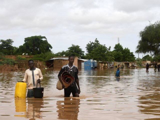 In the Kirkissoye neighborhood in Niamey, people carry their belongings while walking in a street flooded by waters from the Niger river. 