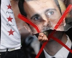 A demonstrator punches through a portrait of Syria's President Bashar al-Assad during a protest outside the Syrian Embassy in London