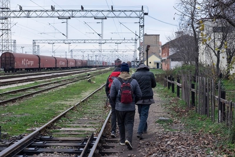 Migrants walking along train tracks in Serbia. Source: Shutterstock.